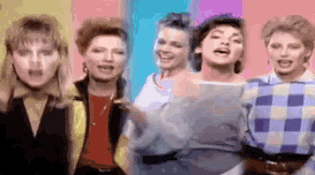 a group of women are standing next to each other on a colorful background and singing .