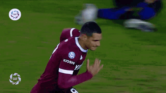 a soccer player in a maroon and white jersey with the word saf on the bottom right