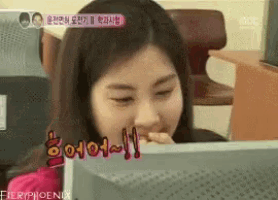 a woman is smiling while looking at a computer screen and says fieryphoenix