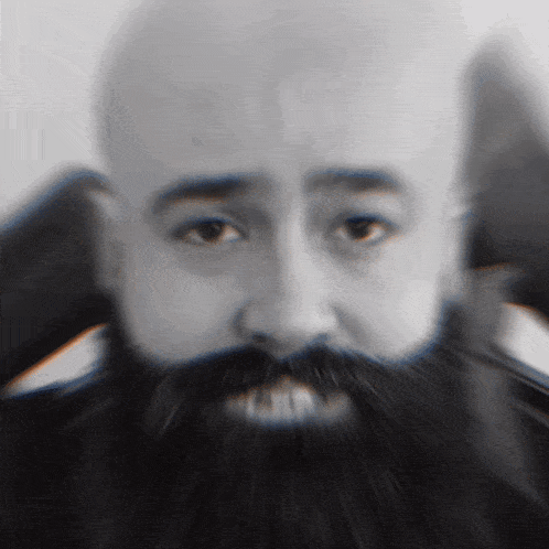 a man with a beard and mustache is covering his ears with his hands
