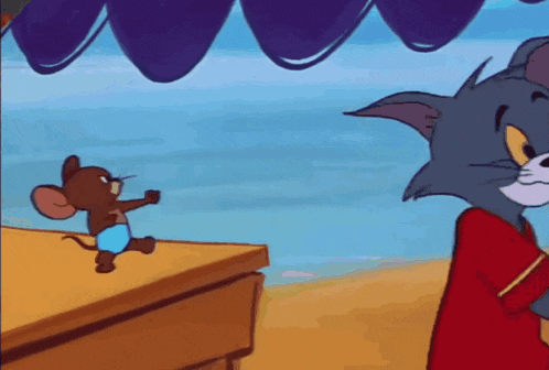 a cartoon mouse is standing on a table next to a striped balloon .