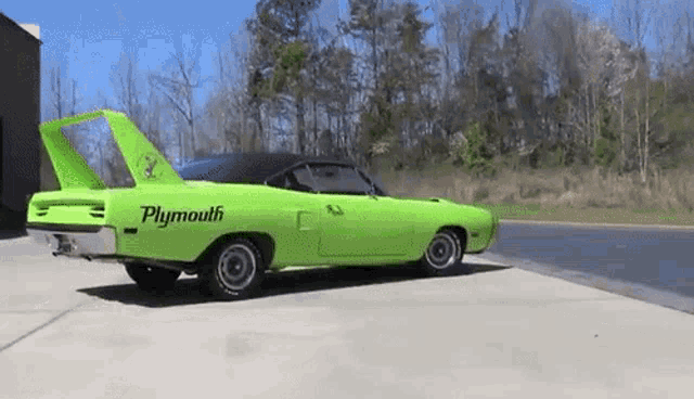 a green plymouth superbird is parked on the side of the road .