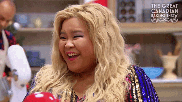 a woman is laughing in front of the great canadian baking show