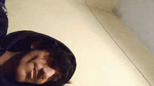 a man in a hooded jacket is laying on the floor .