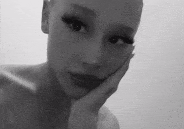 a black and white photo of a woman 's face with her hand on her face