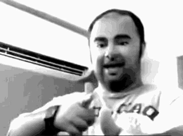 a man with a beard is wearing a t-shirt that says qaq on it .