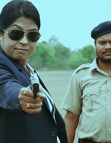 a woman in sunglasses is pointing a gun at a man in a uniform