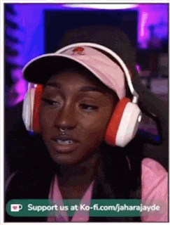 a woman wearing headphones and a hat is sitting in front of a computer screen .