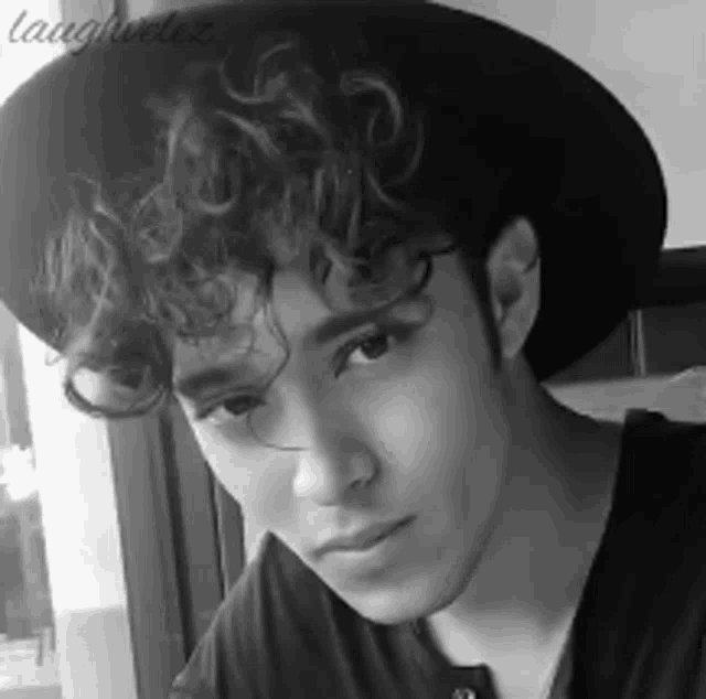 a black and white photo of a young man wearing a hat and a black shirt