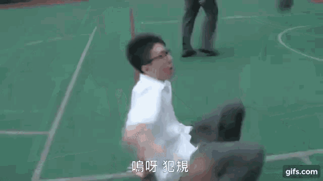 a man in a school uniform is laying on his back on a green field .