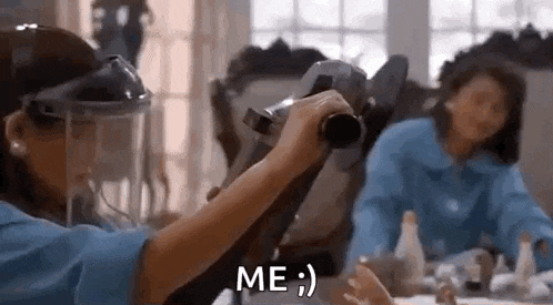 a woman is sitting at a table holding a camera and a child is holding a camera in front of her .