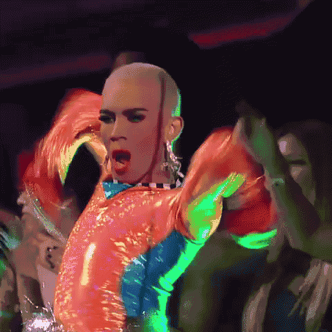 a drag queen is dancing in front of a crowd in a club