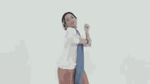 a woman in a white shirt and red skirt is dancing with a scarf around her neck .