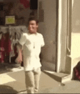 a man in a white shirt is standing in front of a store window .