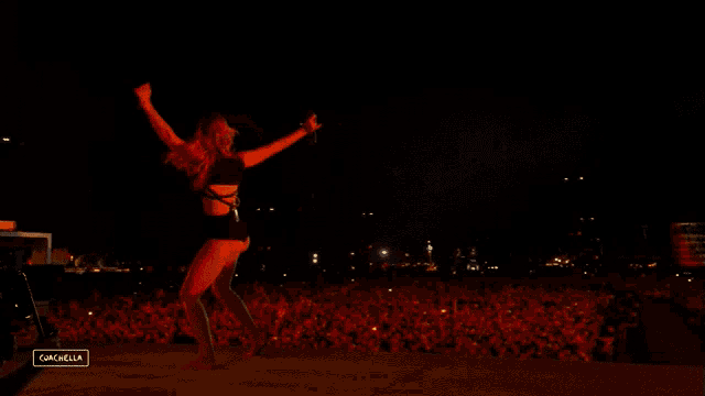 a woman in a black bodysuit is dancing on a stage in front of a crowd at a music festival sponsored by gazelle