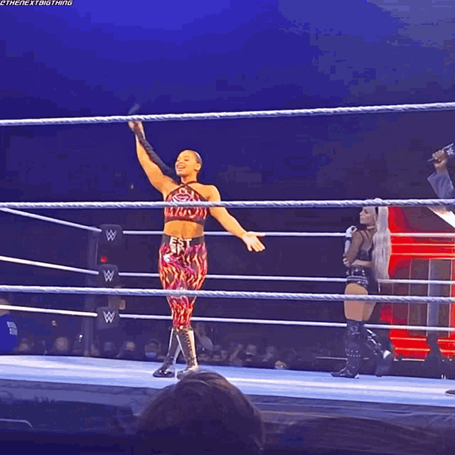 a female wrestler stands in a wrestling ring with her arm up