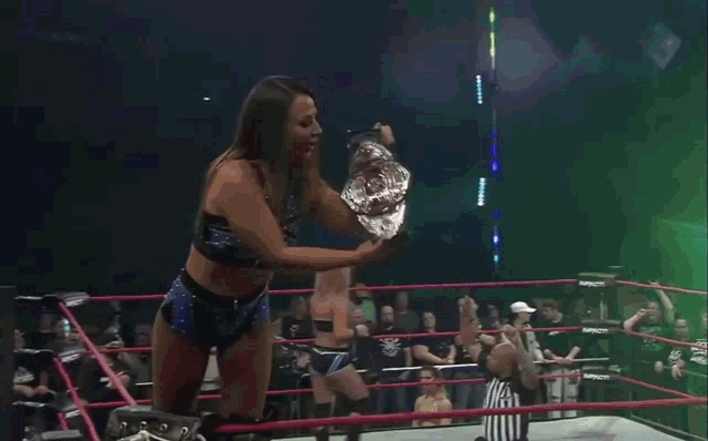 a woman in a wrestling ring with a sign that says impact wrestling on it