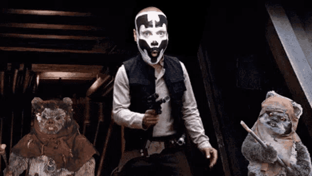a man with a mask on his face is holding a gun next to two ewok bears