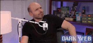 a bald man is sitting in front of a microphone with the words dark web behind him