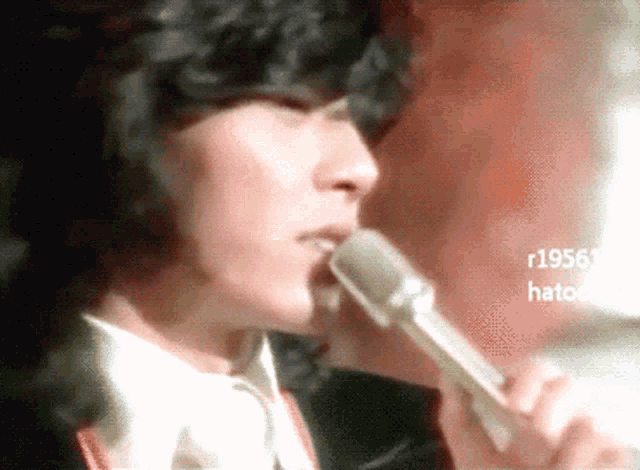 a close up of a person singing into a microphone with the year 1956