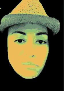 a person wearing a hat with a green background is looking at the camera