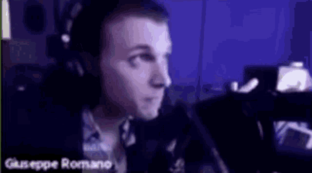 a man wearing headphones and a microphone is sitting in front of a computer screen .