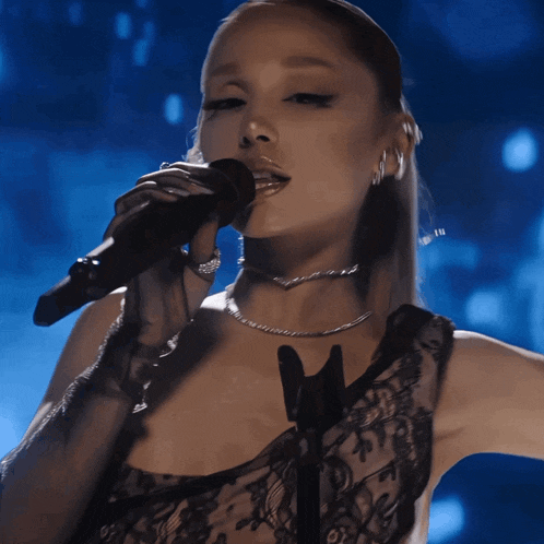 a woman singing into a microphone wearing a black top