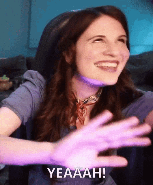 a woman is laughing with her hands outstretched and the words yeaaah are visible