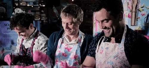 three men wearing aprons and gloves are sitting at a table .