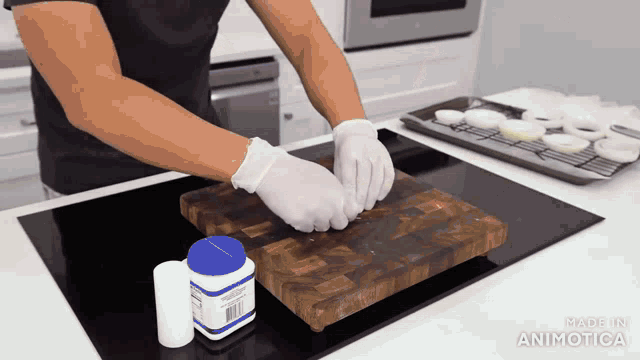 a person is cutting a piece of meat on a cutting board with a bottle of made in animatica on the stove top