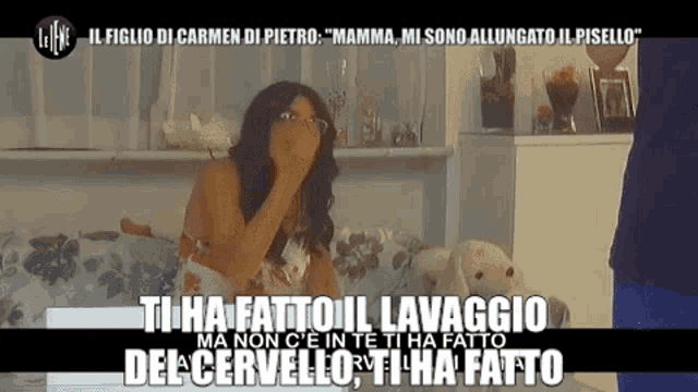 a woman sitting on a bed covering her mouth with her hand and a caption that says ti ha fatto il lavaggio