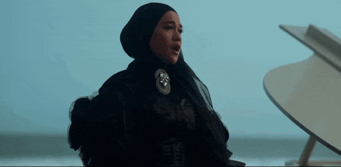 a woman in a black hijab is standing next to a piano