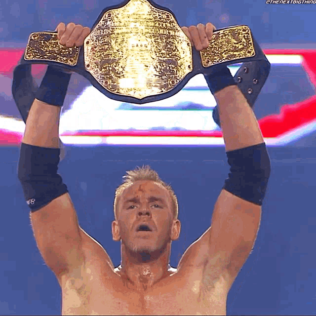 a wrestler is holding a championship belt over his head with a watermark that says the next thing