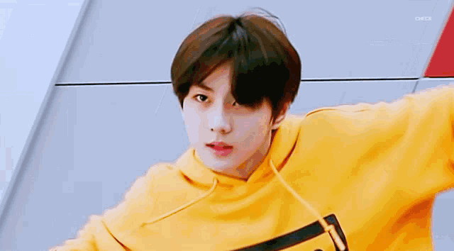 a young boy is wearing a yellow hoodie and looking at the camera .