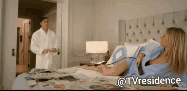 a woman in a blue shirt is laying on a bed next to a man