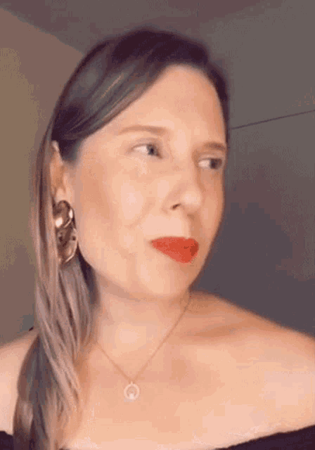 a woman wearing a necklace and earrings is looking at the camera .