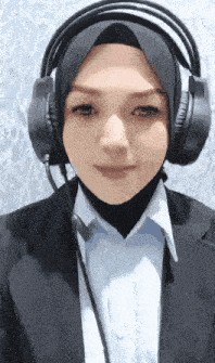a woman wearing headphones and a hijab is smiling .