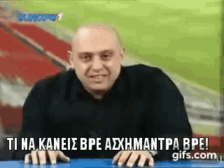 a bald man is sitting at a table with the words ti na kaneis bpe axhmantra bpe on the bottom