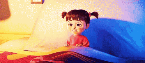 boo from monsters inc is sitting on a bed with a blue blanket