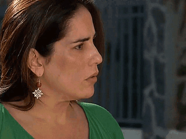a woman wearing a green shirt and earrings has a steering wheel on her earring