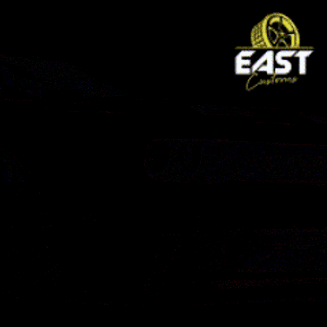 a red car is driving under a bridge with a sign that says east customs