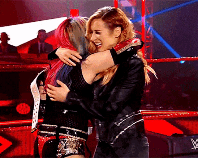 two women hugging each other in a wrestling ring