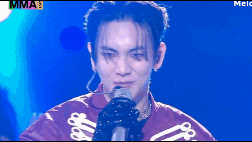 a close up of a person singing into a microphone with the word mma on the bottom