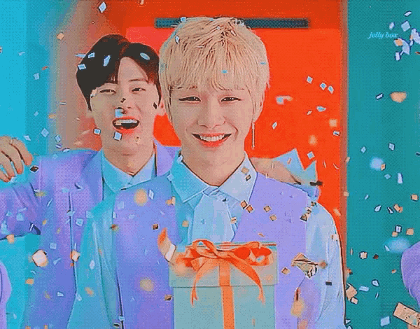 two young men are standing next to each other with confetti falling around them .