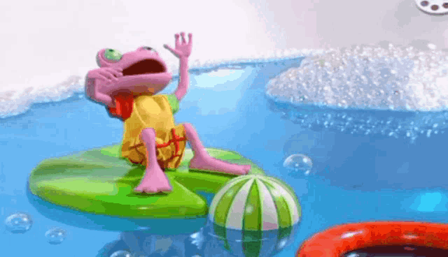 a pink toy frog is sitting on a green raft in a bathtub .