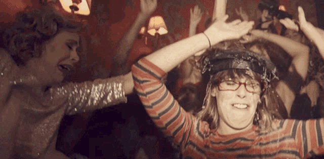 a woman wearing glasses and a striped shirt is dancing at a party