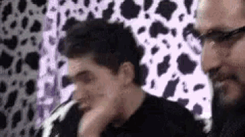 two men are standing next to each other in front of a cow print wall .