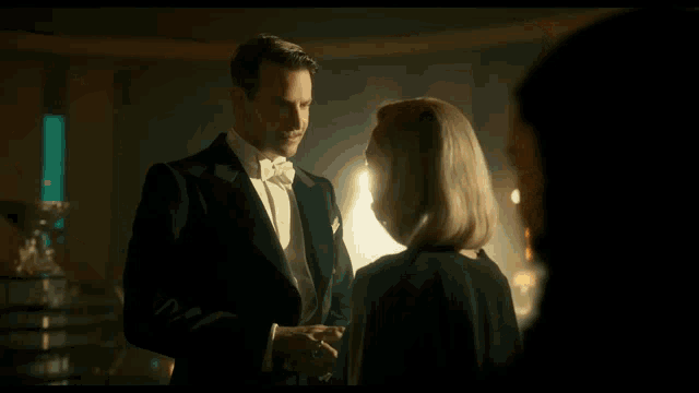 a woman with red lipstick is standing next to a man in a dark room .