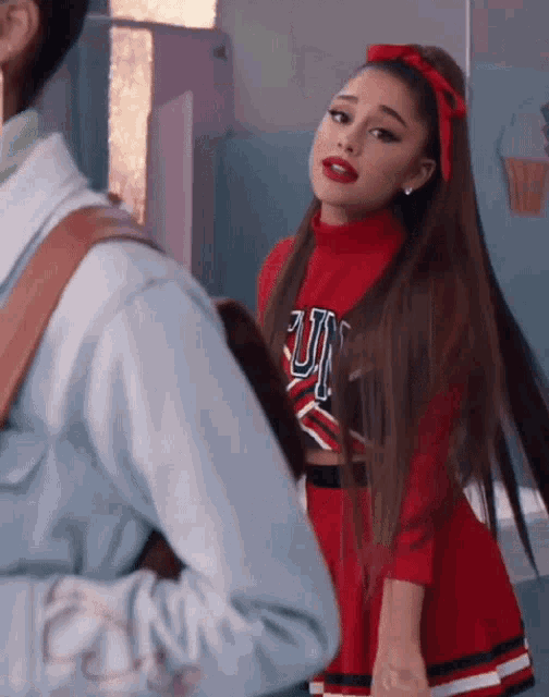 ariana grande is wearing a cheerleader outfit and standing next to a man