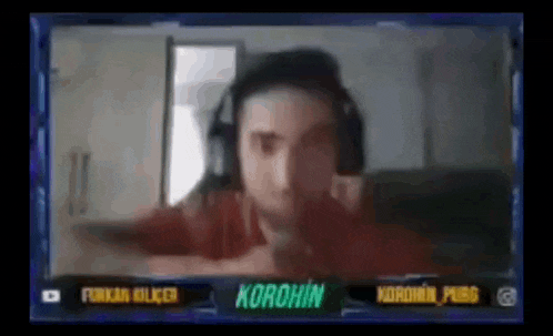a man wearing headphones is sitting in front of a screen that says korohin on it .